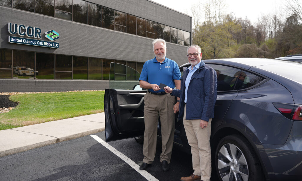 Photo: Ken Rueter and Jay Mullis stand in front of new electric vehicle