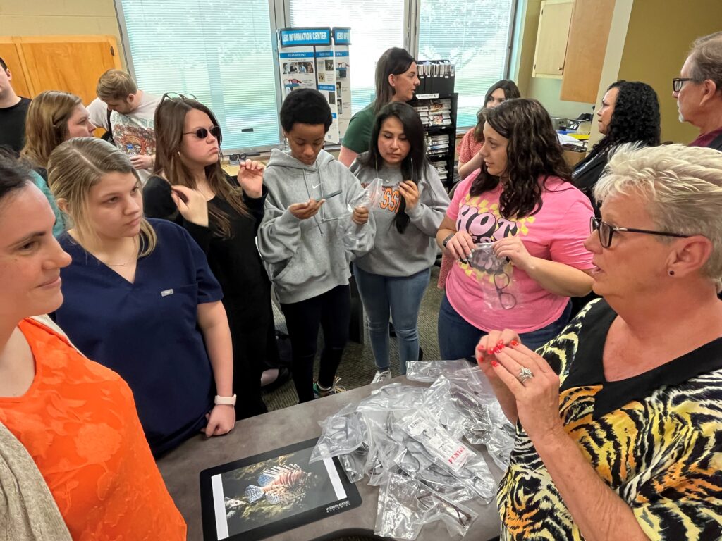 Photo of UCOR’s Lisa Russell speaking with students as they examine the safety glasses that UCOR donated.