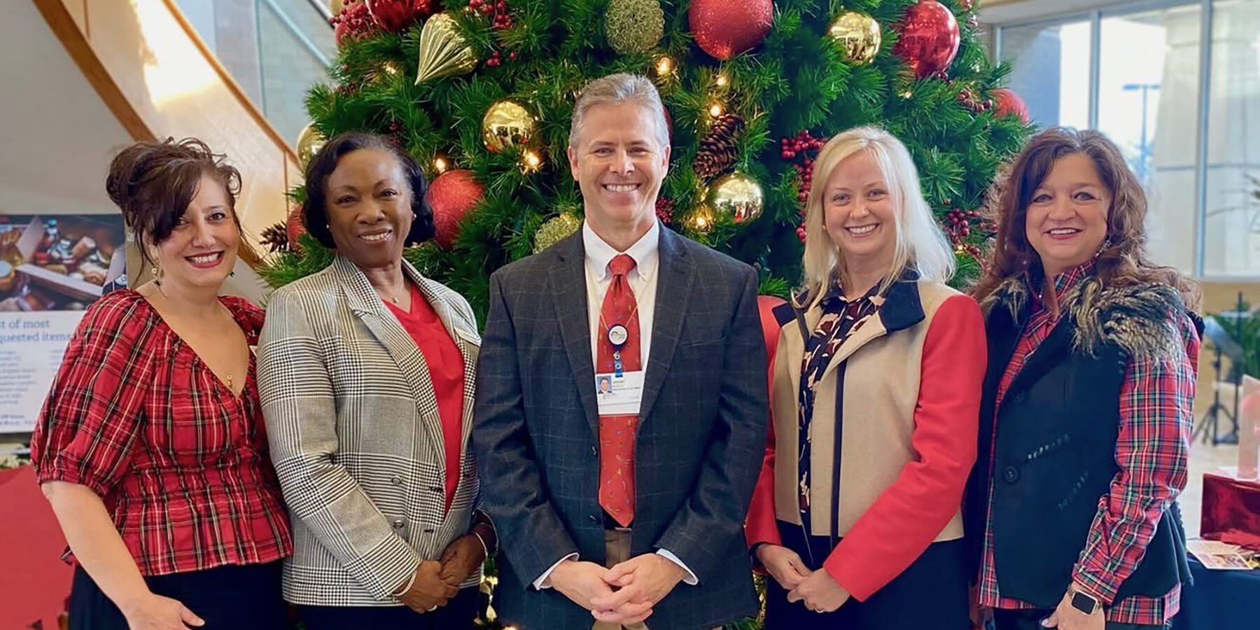 Photo of five people in front of a Christmas tree