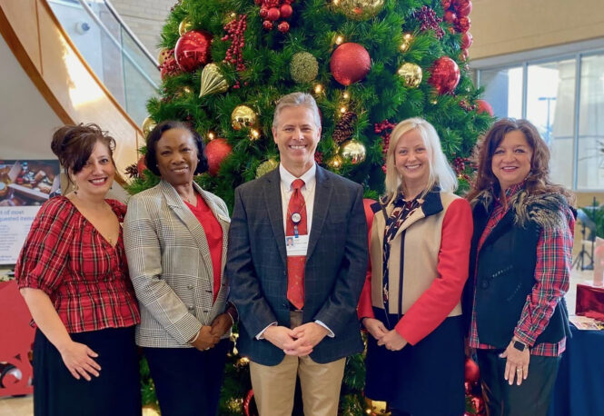 Photo of five people in front of a Christmas tree