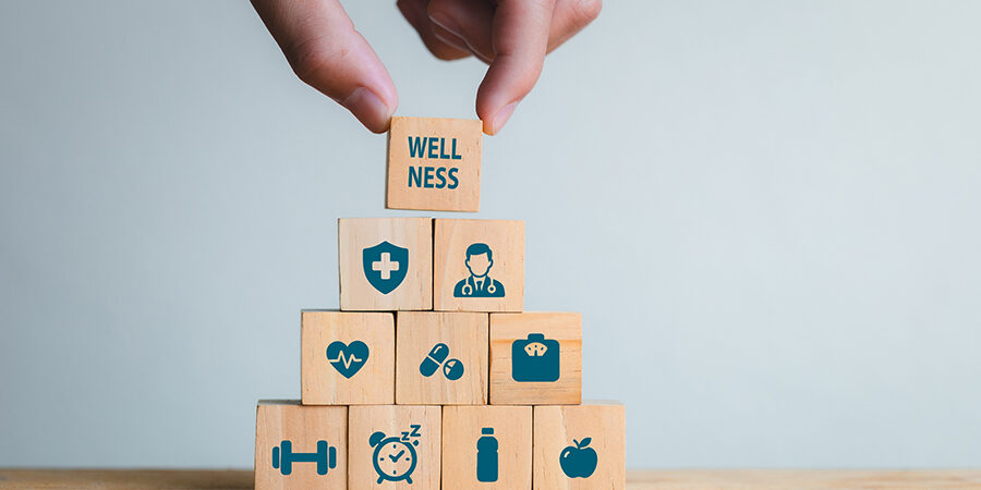 A,Hand,Places,A,Block,Labeled,”wellness”,Atop,A,Stack